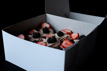 chocolate cupcakes with strawberry and blackberry in a white cardboard box