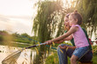© Duche - Sweet little girl and her mother spending fishing time near the river. Mother and daughter in motion catching the fish on the river coast. Low angle view.