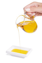 Pouring Oil Into A White Bowl From A Glass Jug In A Female Hand