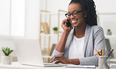 Positive African American Businesswoman Talking On Mobile Working On Laptop