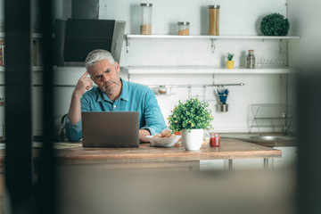 Mature man using laptop computer on kitchen