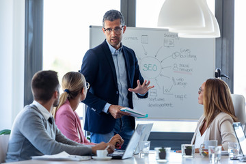 Handsome businessman explaining a project to his colleagues on coworking place.