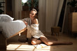 © Yakobchuk Olena - Charming young woman sitting on the floor next to bed