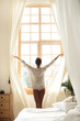 © Yakobchuk Olena - Young lady opening curtains in the morning