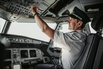 Concentrated pilot in cockpit looking at control panel