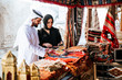 © oneinchpunch - Happy couple spending time in Dubai. man and woman wearing traditional clothes making shopping in the old city