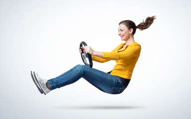 Young happy smiling girl drives a car with steering wheel in hands, auto concept 