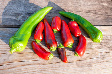 Sweet red and green peppers on a wooden background on a sunny day