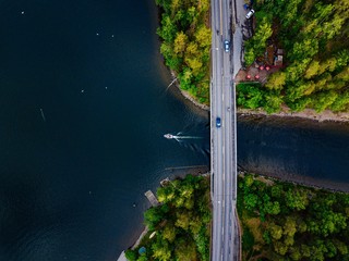 Aerial view of the bridge with a boat passing under it. Blue lake with summer houses in Finland.