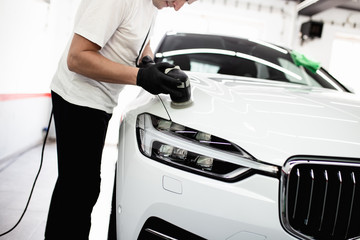 Car detailing - Worker with orbital polisher in auto repair shop. Selective focus.