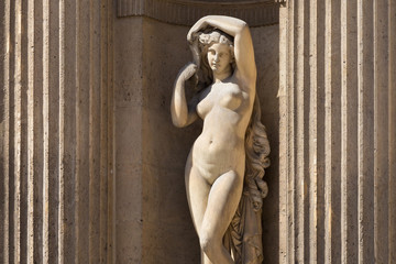 Wall Mural - One of the historical sculptures of the Louvre Palace in street stone niche, Paris, France. Louvre is the world's largest art museum.