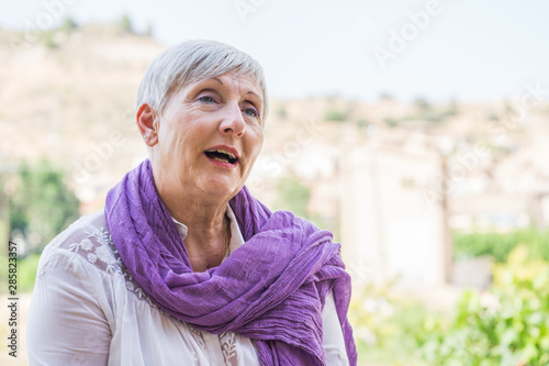 Older Woman With Purple Scarf On Her Neck And White Hair Smiling