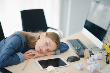 Young beautiful European business woman is sleeping on the table work. Creative woman sleep felling relax after hard work at noon. Co working space concept.