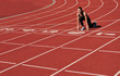 © splitov27 - Young runner woman in sportwear getting ready to run sprint at low start on stadium track with red coated at bright sunny day