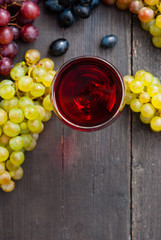 Canvas Print - glass of red wine and grapes on black wooden table background