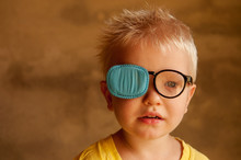 Portrait Of Funny Child In New Glasses With Patch For Correcting Squint .Ortopad Boys Eye Patches Nozzle For Glasses For Treatment Of Strabismus (lazy Eye)