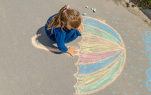 Child Draws With Chalk On The Pavement. Selective Focus.