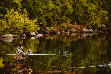 Wall Mural - Fly fishing fisherman caught salmon fish, splashing water