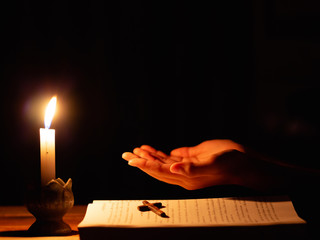 Wall Mural - Human praying to the GOD while with a crucifix symbol with lighting candle at night time.