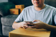 © wutzkoh - Asian young man using smart phone for checking shipment at home.