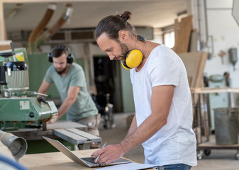 Wall Mural - two worker in a carpenter's workshop using computer