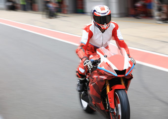 Wall Mural - Racing bike rider on a sports motorcycle back to the pits