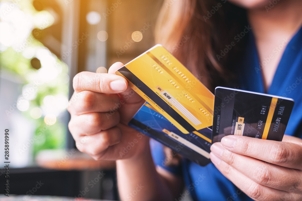 Closeup image of a woman holding and choosing credit card to use - obrazy, fototapety, plakaty 