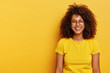 © wayhome.studio  - Isolated shot of happy pretty Afro girl has bushy dark hair, wears big round glasses, bright yellow t shirt, smiles happily, glad to have successful day, models indoor, feels relaxed and carefree