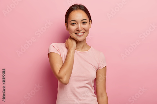 Fotografía Portrait of feminine girl with pleasant smile, gentle look, touches neck, has de