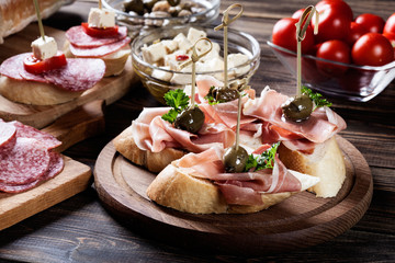 Sticker - Spanish tapas with slices jamon serrano, salami, olives and cheese cubes on a wooden table