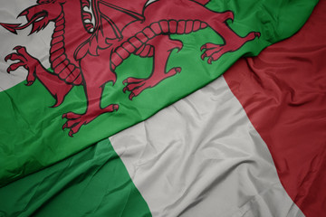 waving colorful flag of italy and national flag of wales.