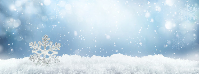 Poster - Festive winter snow background with snowdrifts, silver decorative snowflake with beautiful light and snow flakes on blue sky, banner format, copy space.