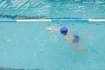 top view of a 7-year boy playing and swimming in the swimming pool