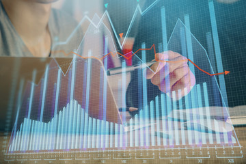 Forex graph with businessman typing on computer in office on background. Concept of analysis. Double exposure.