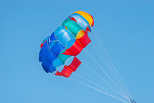 Close Up Shot Of A Colorful Parachute Used For Parasailing Pulled By A Motorboat.