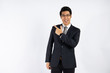 © khwanchai - Smart Asian businessman in suit pointing up for presentation on copy space against white wall in studio