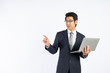 © khwanchai - Smart Asian businessman holding laptop and point copy space for key words against white wall in studio