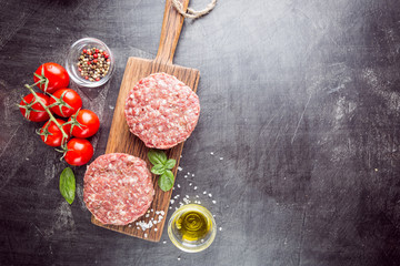 Fresh raw Prime Black Angus beef burger patties on black background. Top view.