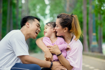 Wall Mural - Little girl laughing with her parents in the park