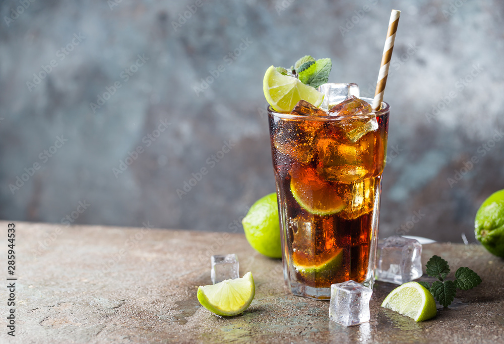 Fresh made Cuba Libre with brown rum, cola, mint and lemon on gray stone background - obrazy, fototapety, plakaty 