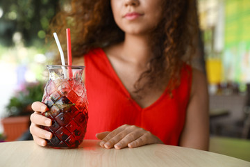 Poster - African-American woman with glass of natural lemonade in cafe, closeup. Detox drink