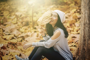 Woman closing face with dried autumn leaves