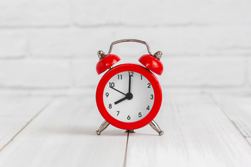 Wall Mural - Alarm clock on white wood table over white brick background with copy space.