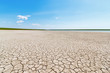 © Alexey Slyusarenko - The surface of the cracked dry ground with the tiny stripe of the water and green grasses on the horizon. Gruzskoe lake, Rostov-on-Don region, Russia