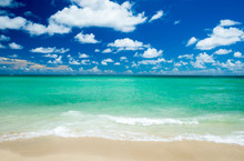Bright Scenic View Of Tropical Caribbean Waves Lapping The Golden Sands Of A Sunny Beach Under Vibrant Blue Sky