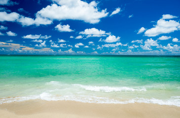 Bright scenic view of tropical Caribbean waves lapping the golden sands of a sunny beach under vibrant blue sky