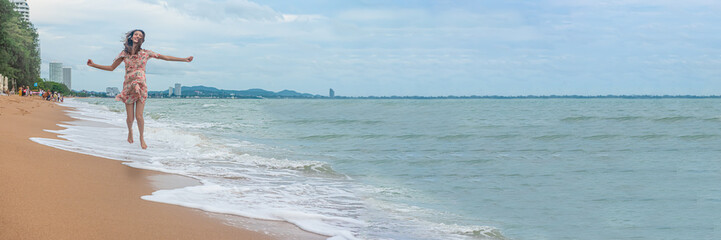 Summer beach vacation holidays trip concept, Happy young Asian woman walking relaxing on the sand of sea beach with wave.