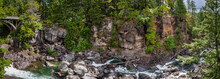 Panorama Of A Bridge On The Left With A Creek Running Between Boulders In A Narrow Steep Canyon In A Dense Forest Near The Rogue River In Oregon
