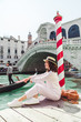 woman sitting near rialto bridge in venice italy looking at grand canal with gondolas