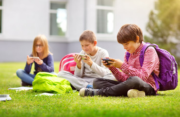 Wall Mural - Children with rucksacks sitting in the park near school